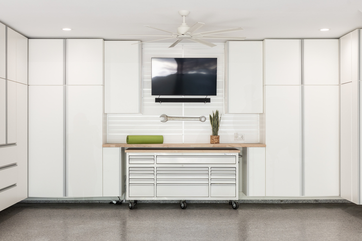 Garage with lanai grey flooring and white cabinets that have a light wood worktop.
